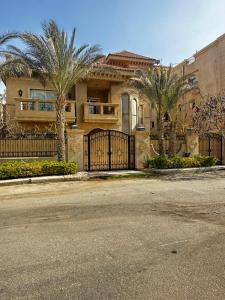 a large house with a gate and palm trees at Heaven new Cairo Villa with Private pool and jacuzzi in Cairo