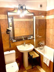 a bathroom with a sink and a toilet and a mirror at Apartamente Arcul de Triumf in Bucharest