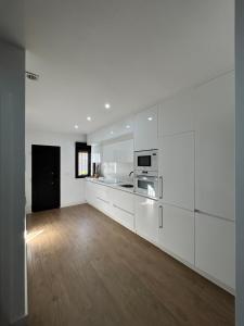 a kitchen with white cabinets and a wooden floor at Center Luxury Chalet Mazagón in Mazagón