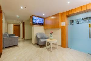 a lobby with two chairs and a table and a tv at Hotel Kurla Suites in Mumbai