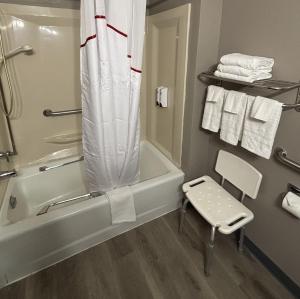 a bathroom with a tub and a chair and towels at Red Roof Inn & Suites Hammond, IN in Hammond +26 photos