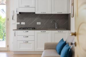 a kitchen with white cabinets and a sink and a couch at Cava Li Santi Residence a Santa Caterina in Nardò