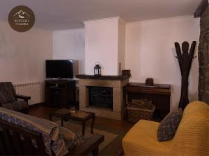 a living room with a fireplace and a television at Refúgio da Geira in Campo do Gerês