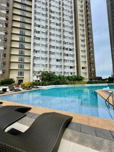 a swimming pool with chairs and a large building at The Suite Pod I CDO CondoStaycation - U26 in Cagayan de Oro