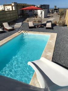 a blue swimming pool with lounge chairs and an umbrella at Sur in Barra de Portezuelo
