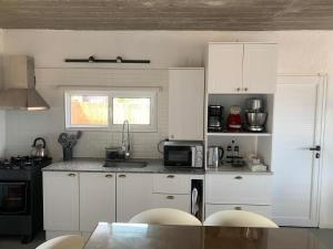 a kitchen with white cabinets and a table with chairs at Sur in Barra de Portezuelo