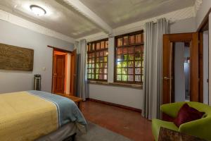 a bedroom with a bed and a chair and windows at Casa Historica Atitlán in Panajachel