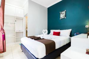 a bedroom with a large bed with a blue wall at Fast Hous Syariah Bogor Mitra RedDoorz in Bogor