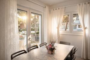 a dining room table with a vase of flowers on it at Villa Greif Apartment in Lignano Sabbiadoro