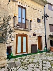 a stone building with a balcony and a door at La Neviera Apulia Rooms in Altamura