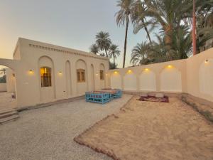 a building with a courtyard with blue tables and palm trees at Talia gust house in Al Aqālitah