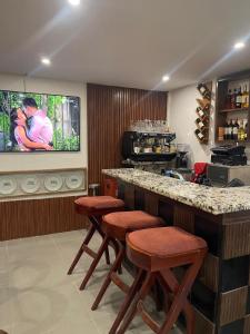 a kitchen with a bar with stools and a tv at SOFT HOTEL in Douala