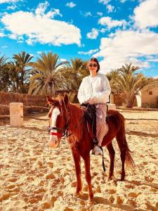 a woman riding a horse on the beach at Aghurmi Siwa Hotel in Siwa