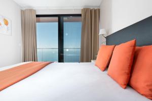 a bedroom with a large bed with orange pillows at Elísio do Mar by LovelyStay in Prazeres +50 photos