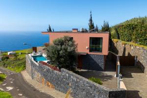 a house on the side of a hill with a wall at Elísio do Mar by LovelyStay in Prazeres
