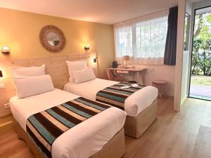 a hotel room with two beds and a mirror at Sure Hotel by Best Western Biarritz Aeroport in Biarritz