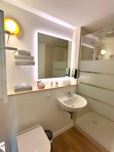 a bathroom with a sink and a mirror at Sure Hotel by Best Western Biarritz Aeroport in Biarritz