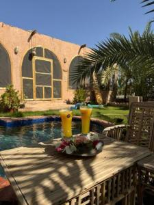 a table with two glasses on top of it next to a pool at The Green Mirage free pickup in Siwa
