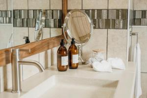 two bottles of wine sitting on a bathroom sink at House Olive in De Kelders +37 photos