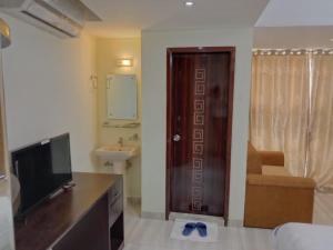 a room with a television and a bathroom with a sink at White Park Boutique Hotel in Chittagong