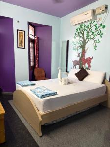 a bedroom with a large bed with purple walls at Mango Tree Homestay in Hampi