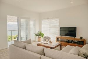a living room with a couch and a flat screen tv at House Olive in De Kelders