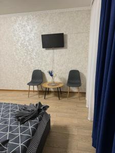 a bedroom with a bed and two chairs and a table at Апартамент с джакузи in Khmelnytskyi