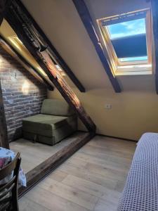 a attic room with a bed and a window at Apartment By the River in Niš