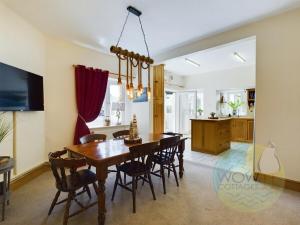 a dining room and kitchen with a wooden table and chairs at Haslemere Cottage, Beer – Coastal Getaway Near the Beach in Beer