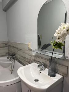 a bathroom with a sink and a vase with white flowers at Апартамент с джакузи in Khmelnytskyi