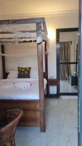 a bedroom with a canopy bed and a mirror at Terrys villa pool view room in Kidoti +16 photos