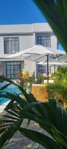 a white building with an umbrella next to a pool at Terrys villa pool view room in Kidoti