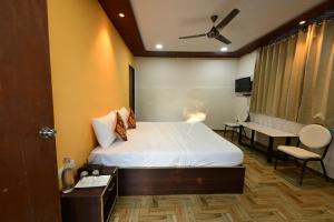 a hotel room with a bed and a desk and a table at Rudrakshi Inn in Mount Ābu