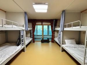 a room with three bunk beds and a window at 파노라마 스테이 in Paranjang