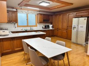 a kitchen with a table and chairs and a refrigerator at 파노라마 스테이 in Paranjang