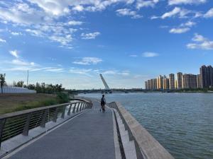 a person walking on a sidewalk next to a body of water at 春江屿舍 in Xi'an
