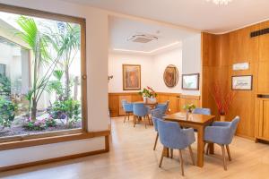 a waiting room with tables and chairs and a large window at Hotel L'Approdo in Castiglione della Pescaia