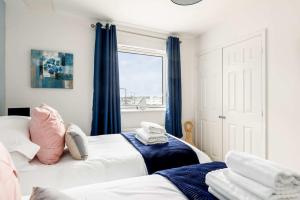 a bedroom with two beds with blue curtains and a window at Harbourside Retreat - Spacious Balcony with Harbour Views in Poole