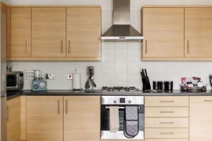 a kitchen with wooden cabinets and a stove top oven at Harbourside Retreat - Spacious Balcony with Harbour Views in Poole