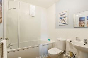 a white bathroom with a shower and a toilet and a sink at Harbourside Retreat - Spacious Balcony with Harbour Views in Poole +26 photos