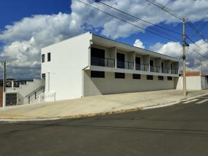 a white building on the side of a street at Studios Leme 11 - conforto para casal - com varanda in Espirito Santo Do Pinhal