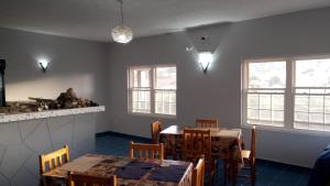 a dining room with two tables and two windows at Djabraba's Triplex in Vila Nova Sintra +21 photos