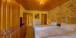 a bedroom with two beds and a stone wall at Къща за гости "Панорама" Проглед in Smolyan