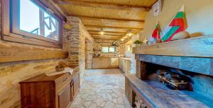 a kitchen with a fireplace in a log home at Къща за гости "Панорама" Проглед in Smolyan