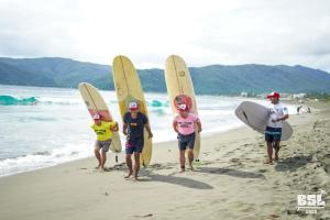 a group of people standing on the beach with their surfboards at North Shore Surf Camp in Baler