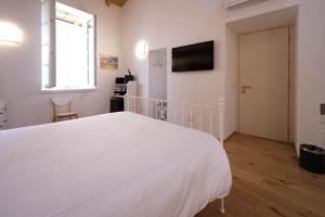 a white bedroom with a large white bed and a window at Locanda Alberti in Mandello del Lario