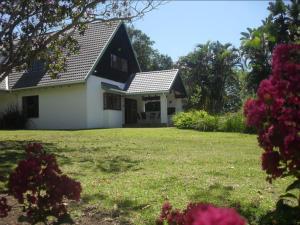 a white house with a black roof and a yard at Bellevue Guest Lodge in Southbroom