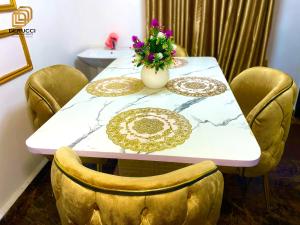a table with chairs and a vase with flowers on it at Derucci Luxury Apartment in Owerri