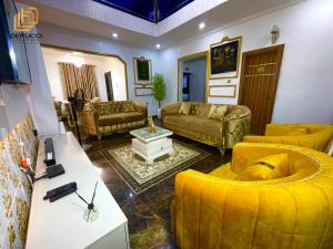 a living room with yellow couches and a table at Derucci Luxury Apartment in Owerri +3 photos