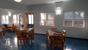 a dining room with tables and chairs and windows at Djabraba's Rooms in Vila Nova Sintra +35 photos